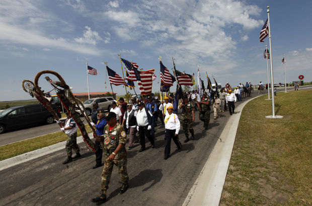 Tribal members carry staffs and flags Wednesday into the Akicita Owicahe Lakota Freedom Veterans Cemetery eight miles east of Kyle for a dedication ceremony. The tribal veterans cemetery is the second of its kind in the nation and was funded by a grant from the Department of Veterans Affairs.